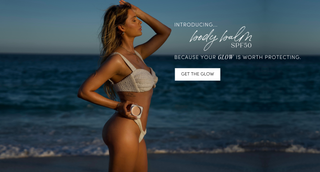 Dolce Glow Body Balm SPF 50 — Open product being applied, showcasing its enhancing formula by the beach - Introducing the body balm SPF50, because your glow is worth protecting - Get the Glow.