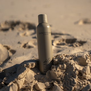 Dolce Self-tanning spray sitting on the sand