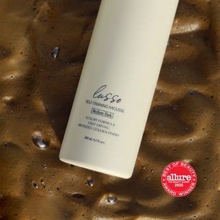 Dolce Glow Lusso self-tanning mousse bottle on a textured brown surface with Allure Best of Beauty award badge.