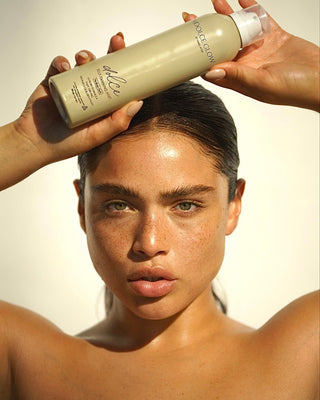 
  
    Dolce Glow – Model with Radiant Skin Holding a Dolce Glow Tanning Bottle
  
