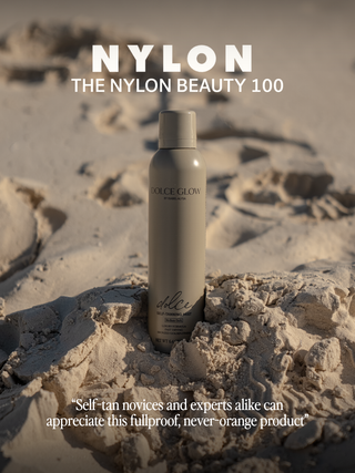 Dolce Glow wins The Nylon Beauty 100. Self-tan spray stands upright on a sandy beach mound.