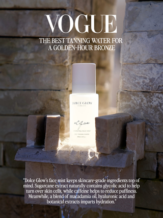 Dolce Glow 'Acqua' face mist named VOGUE Best Tanning Water for a golden hour bronze. Acqua bottle displayed on a rustic stone shelf.