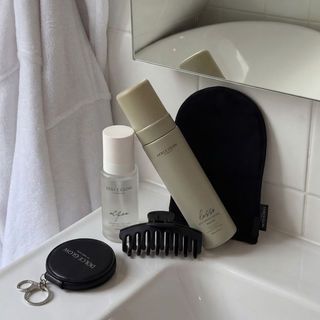 Dolce Glow Travel bundle on bathroom counter including a Lusso mousse, Acqua tanning water, application mitt hair clip and mirror.